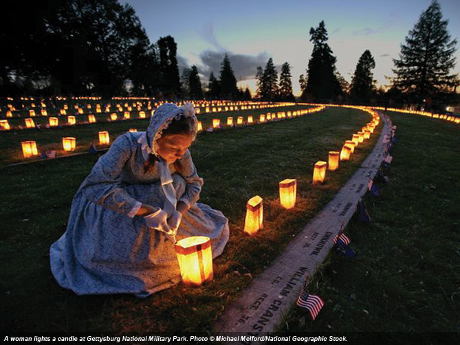 A woman lights a candle at Gettysburg National Military Park