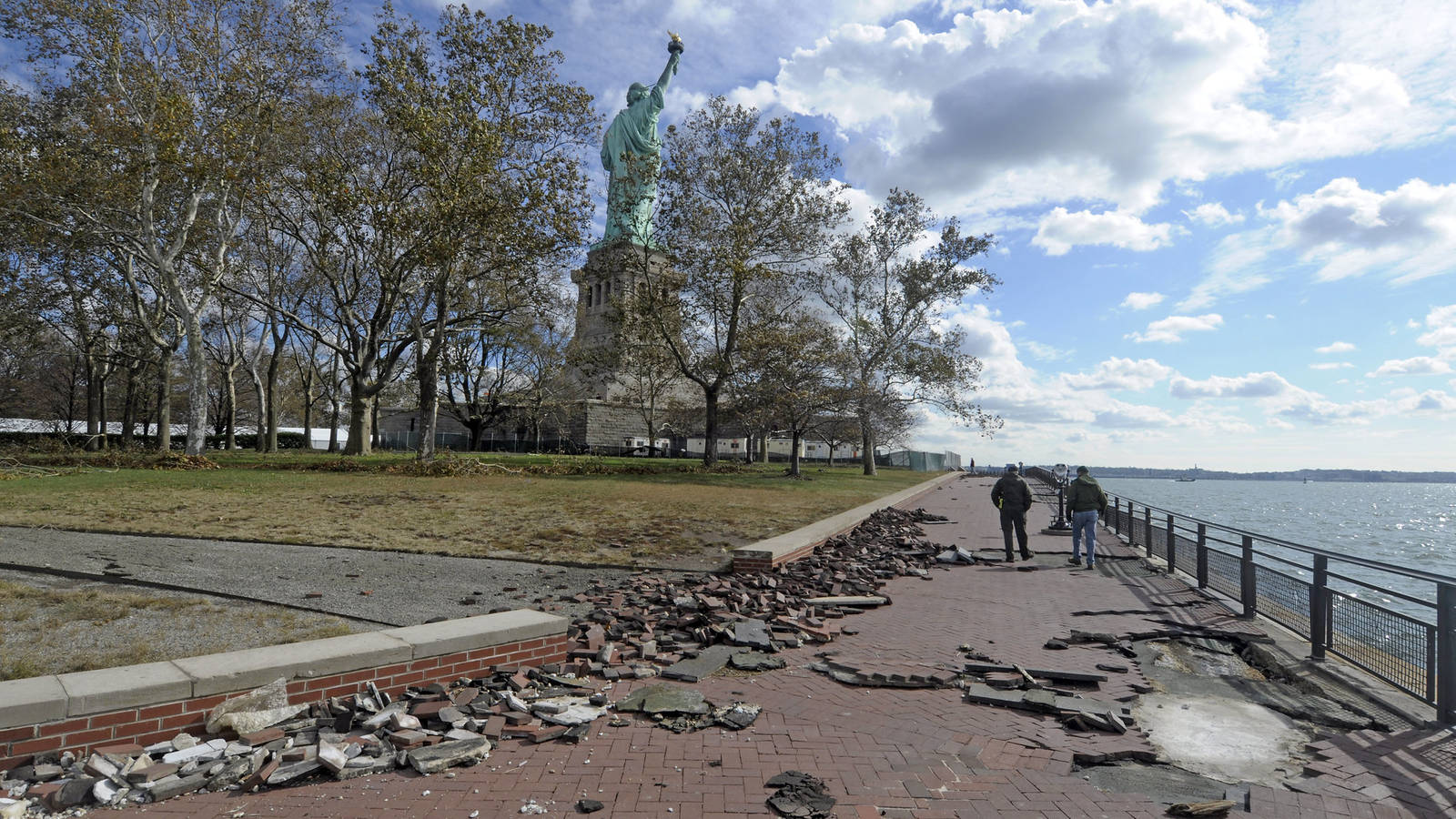 <p>NPS Incident Management Team walk along the southern walkway of Liberty Island to assess the damage following Superstorm Sandy in 2012. Paving bricks were uplifted and underlying pavement damaged during the storm.</p>