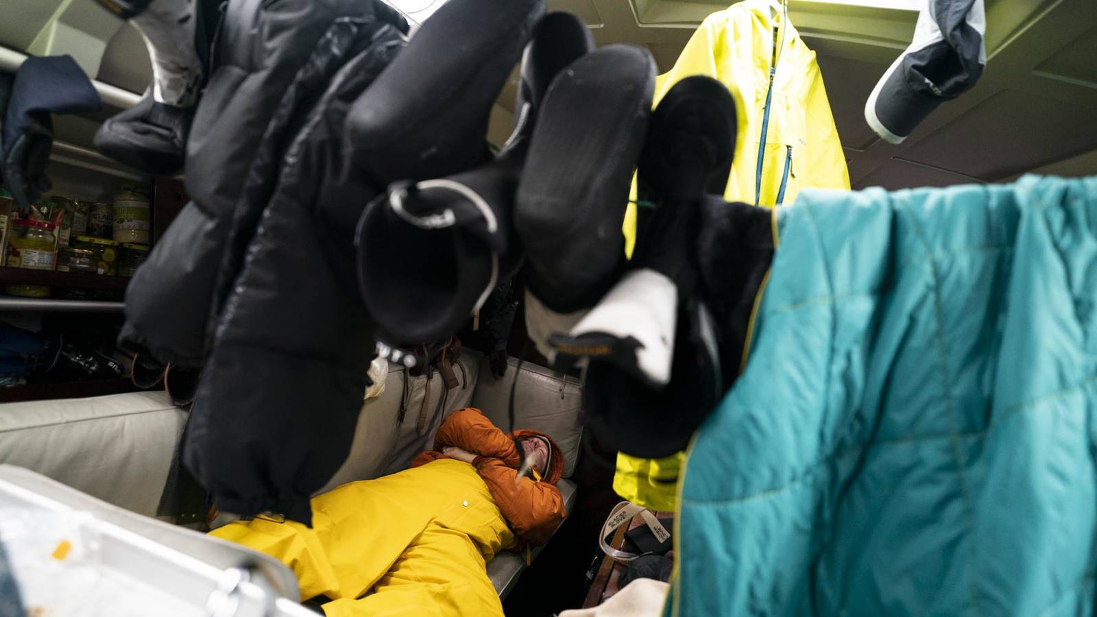 <p>Baldwin Goodell relaxes below deck as various items of apparel hang from makeshift laundry lines. Condensation was a fact of life in the cabin. Wet weather and five people’s breathing combined to make drying clothes nearly impossible. </p>