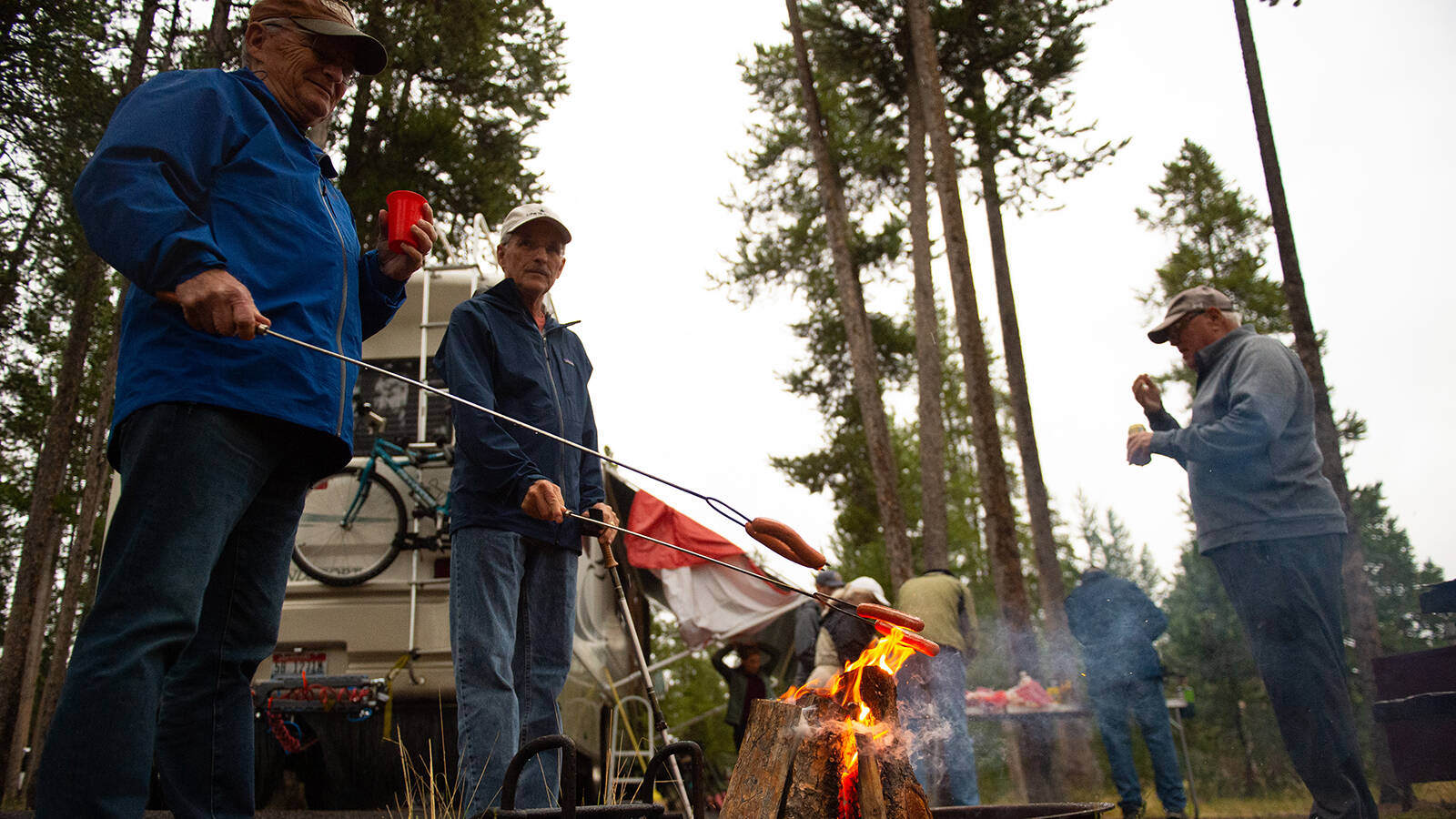 <p>Brothers Cliff Huffman (left) and Dave Huffman roast hot dogs at the Madison Junction campground in August 2022. The brothers worked together as bellmen at Old Faithful Inn in the 1970s.</p>