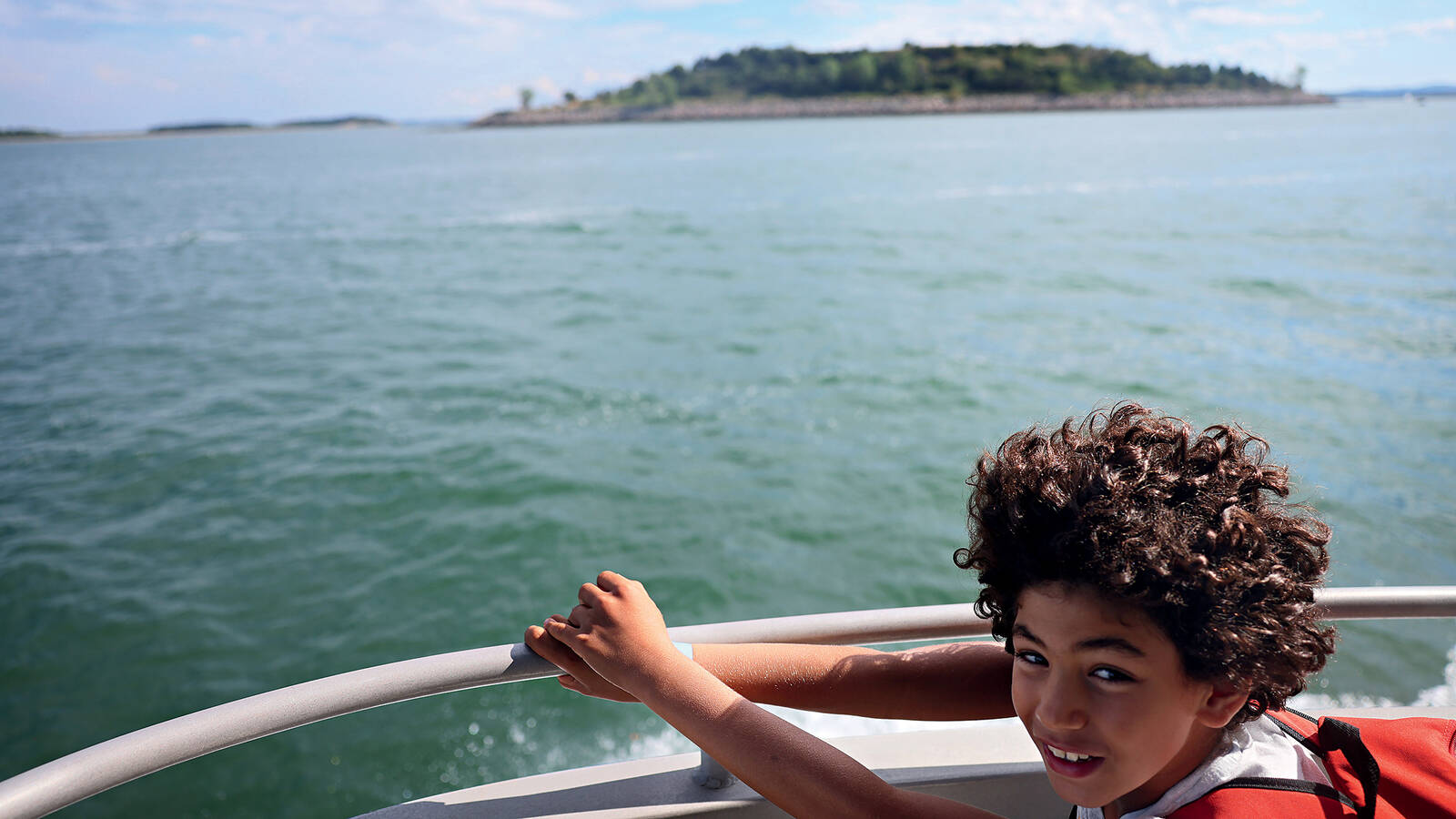 <p>Youssef Elhabbak stands at the bow of a ferry on his way to Peddocks Island, one of 34 islands and peninsulas that make up Boston Harbor Islands National Recreation Area.</p>