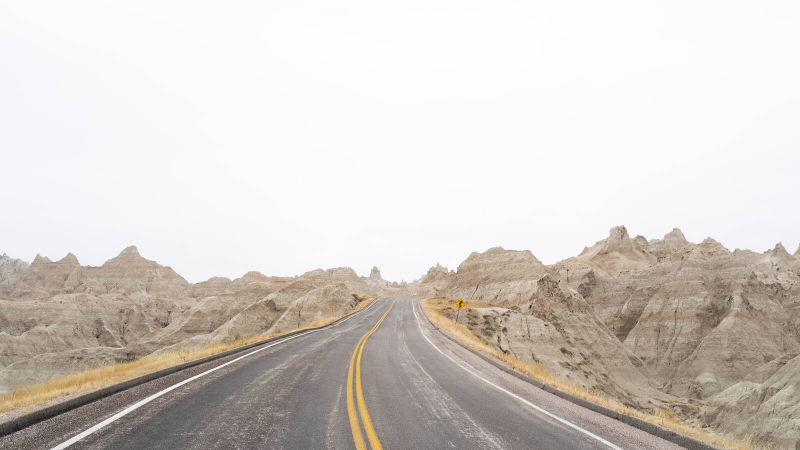 <p>An open road in Badlands National Park. After the storm, those double yellow lines would be nearly impossible to see, leading the brothers to hold open the car door at times.</p>