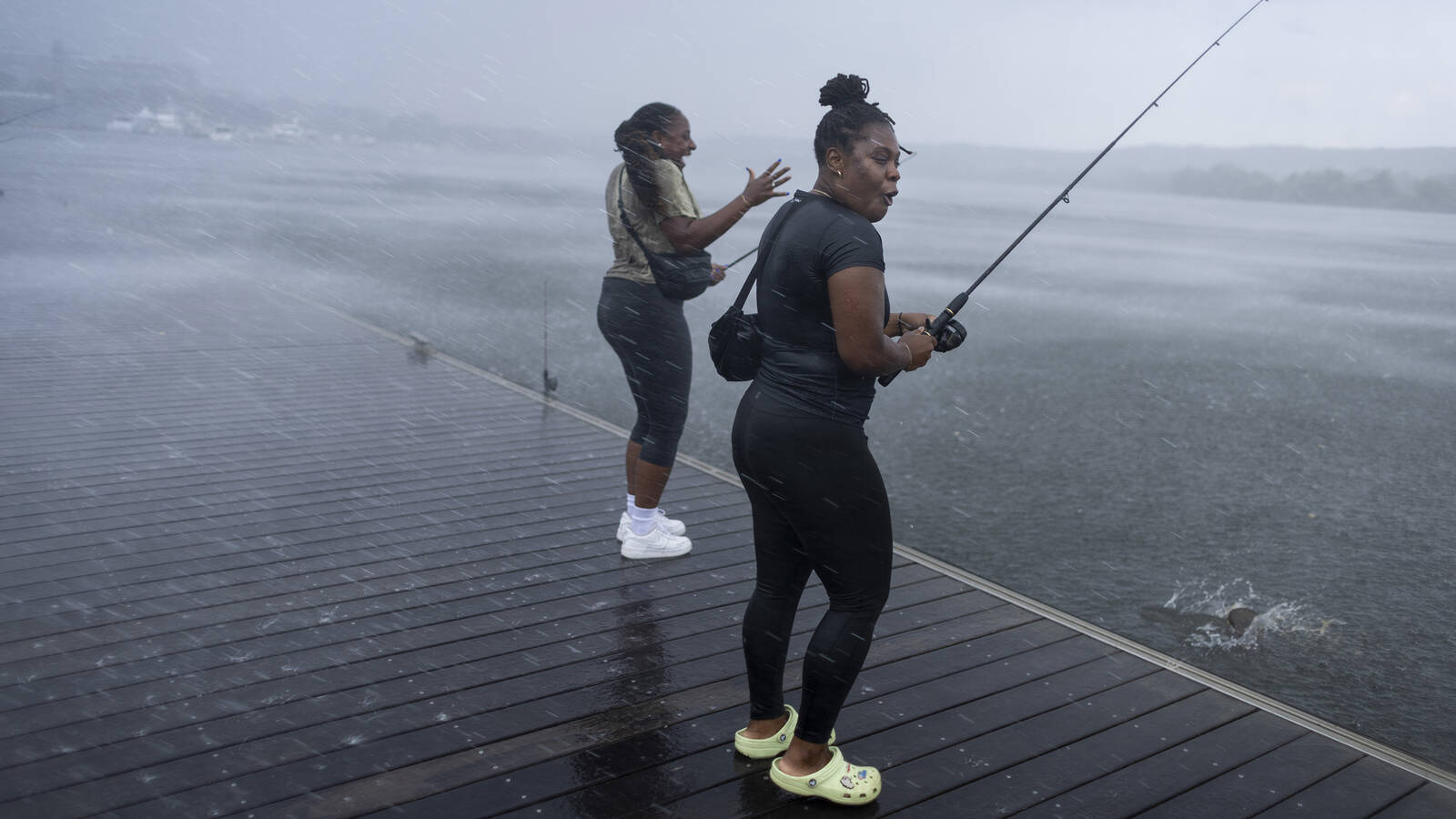 <p>Jazmine Thomas, left, and Ashley Rodgers at Friday Night Fishing, a free, catch-and-release event hosted by Anacostia Riverkeeper during the summer months. When a temperate evening suddenly turned stormy, they were reluctant to leave because they were having such a good time. They were the last pair out on the dock.</p>