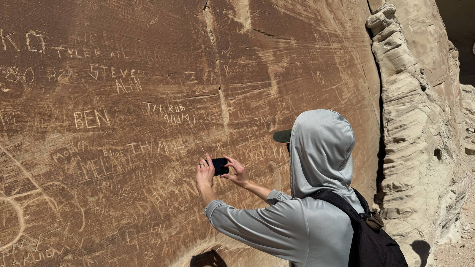<p>Volunter coordinator Alex Anderson documents a wall of graffiti.</p>