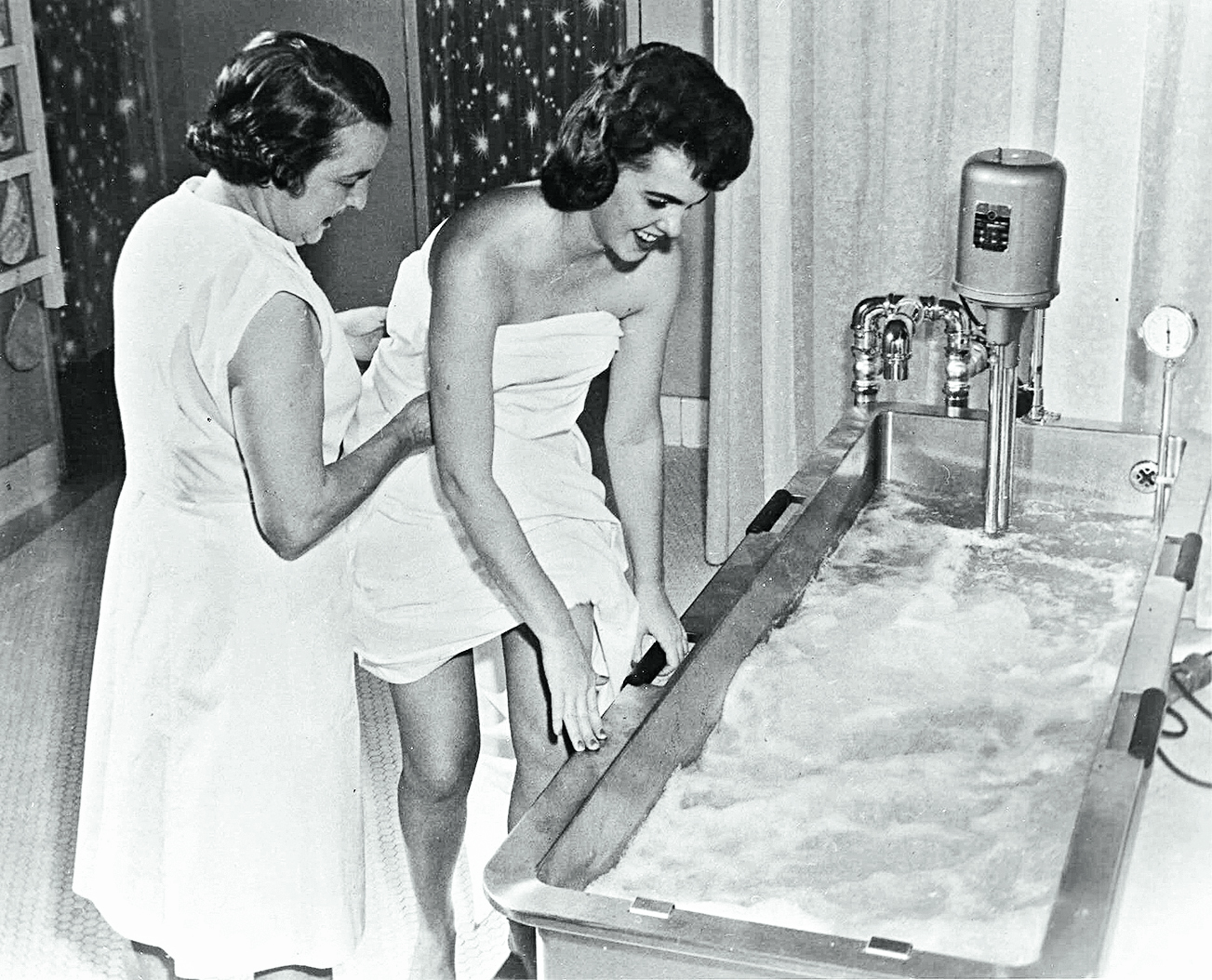 A woman is assisted into a bath at Ozark Bathhouse in 1960.