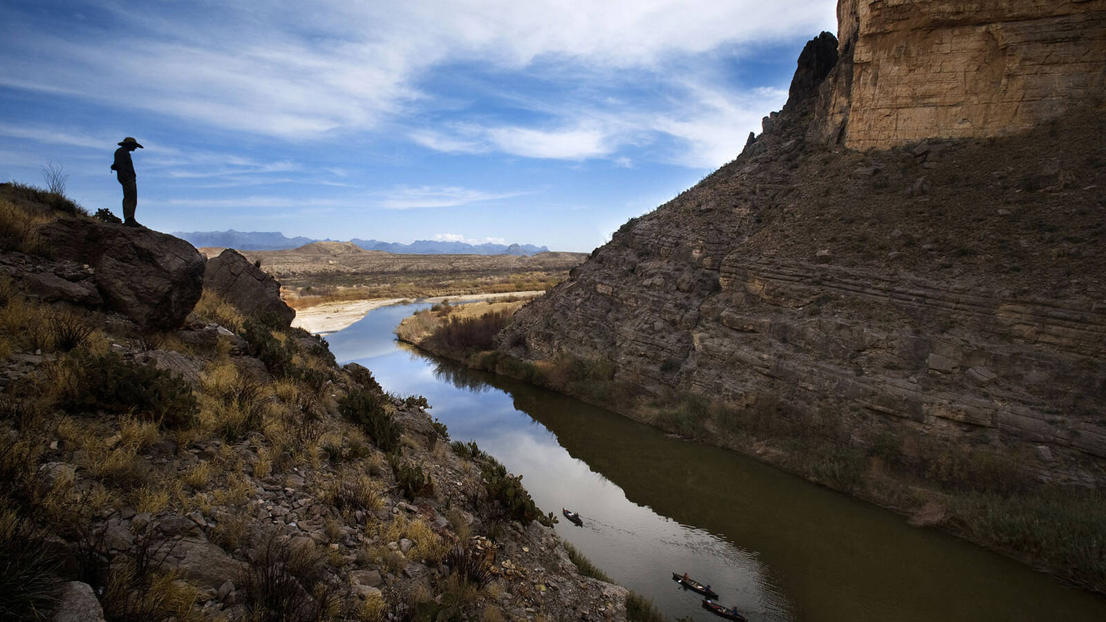 <p>A man is silhouetted in Big Bend National Park's Santa Elena Canyon as he looks down at the Rio Grande. The canyon divides Mexico and the United States. </p>
